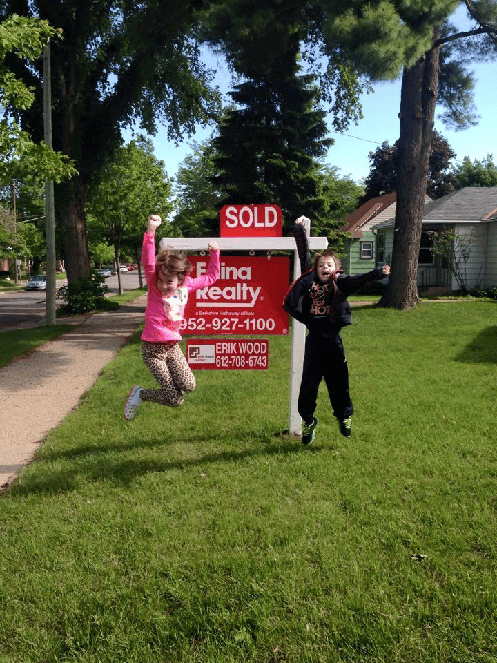 Kids jumping by real estate sold sign